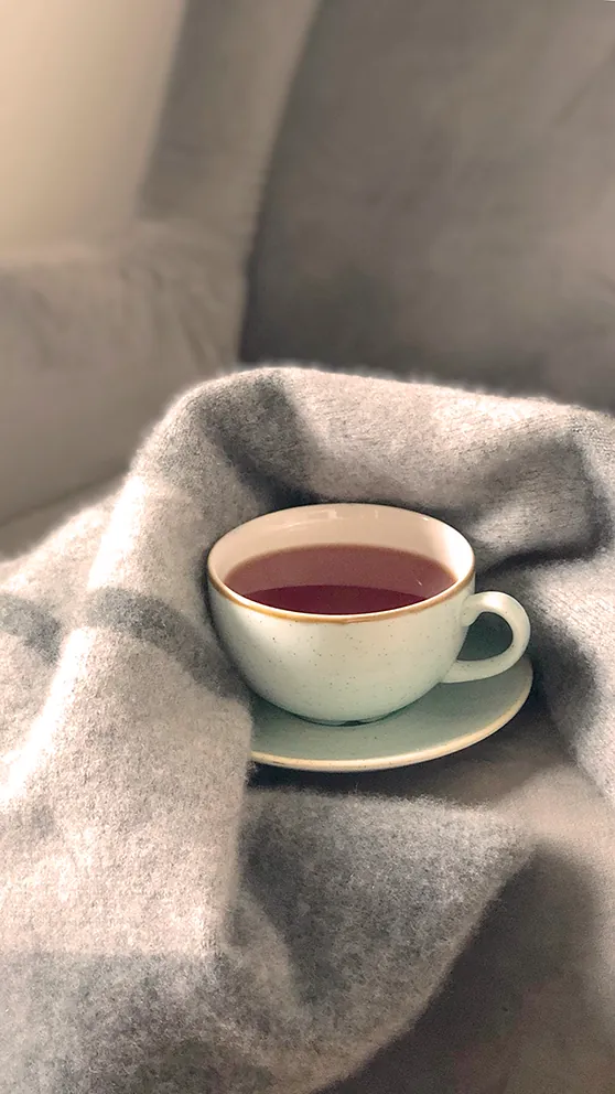 Une tasse de tisane posée sur un plaid en laine